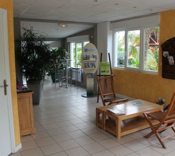 Intérieur lumineux avec sièges et plantes vertes.