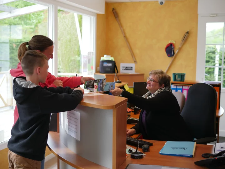 Client reçoit brochures au comptoir d'accueil.