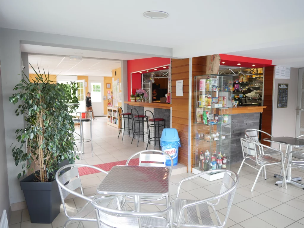 Café moderne avec plantes et tables en métal.