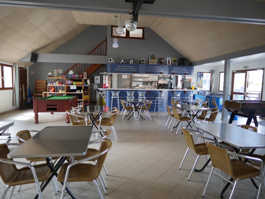 Salle commune avec tables, bar et billard.