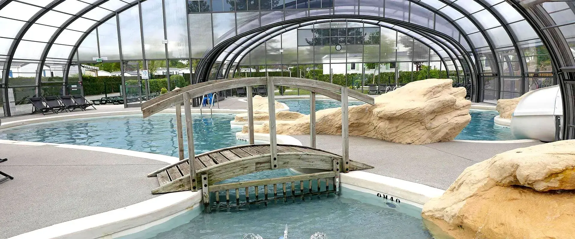 Piscine intérieure avec rochers et passerelle en bois