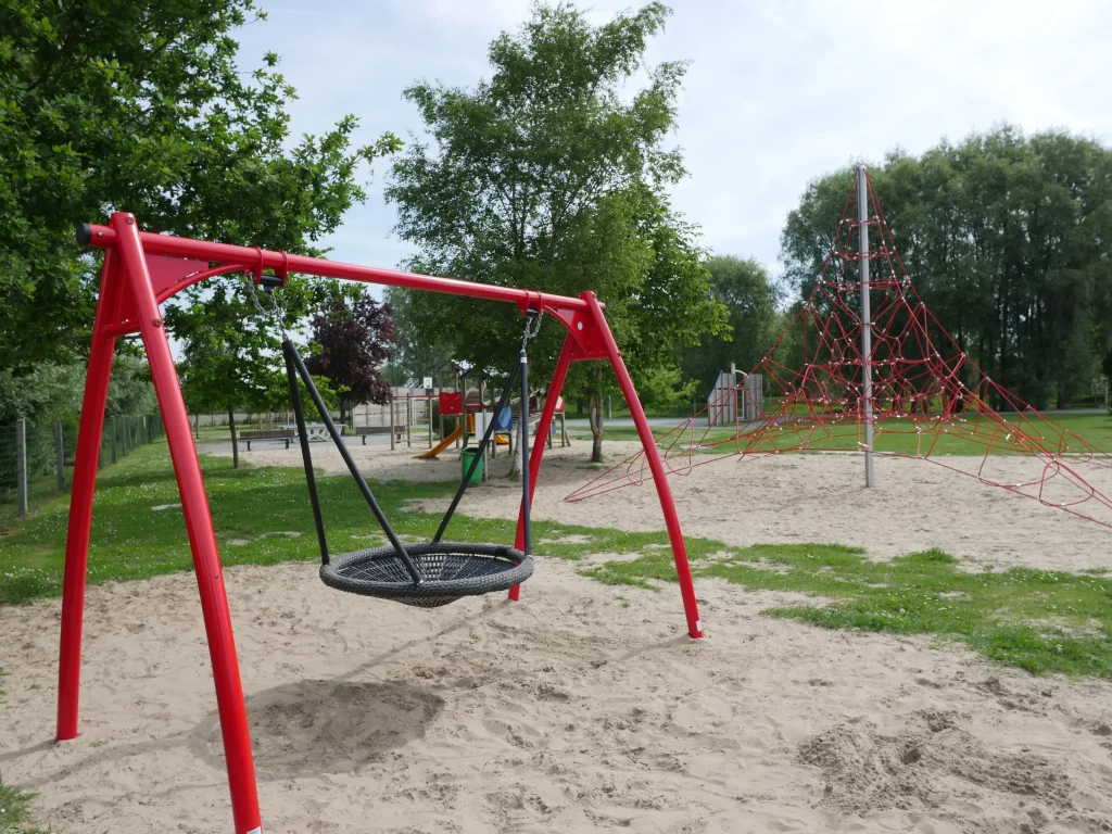 Aire de jeux avec balançoire et filet d'escalade.