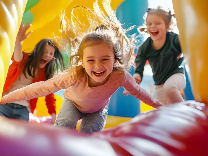 Enfants riant dans un château gonflable coloré.
