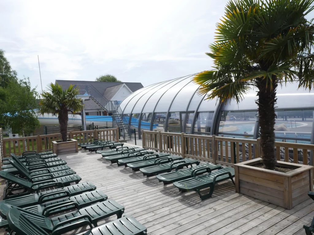 Terrasse avec transats et piscine couverte.