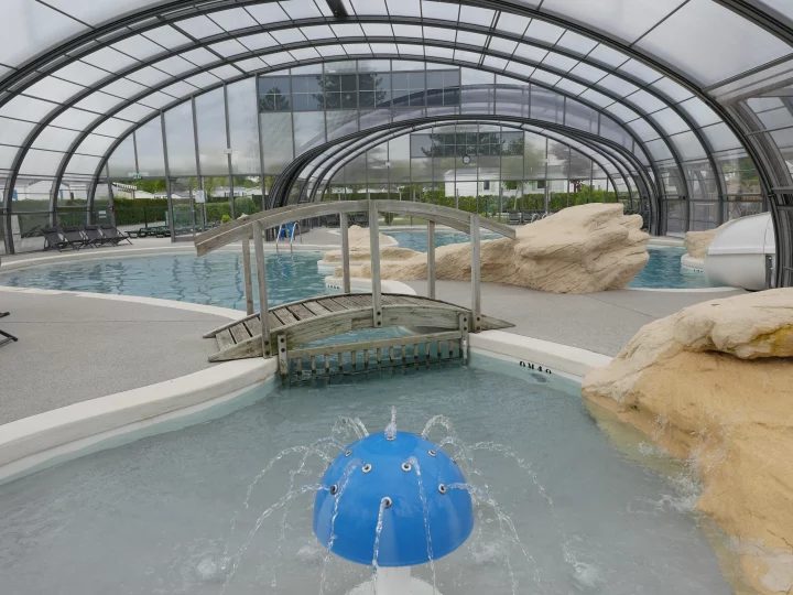 Piscine intérieure avec pont et jets d'eau.