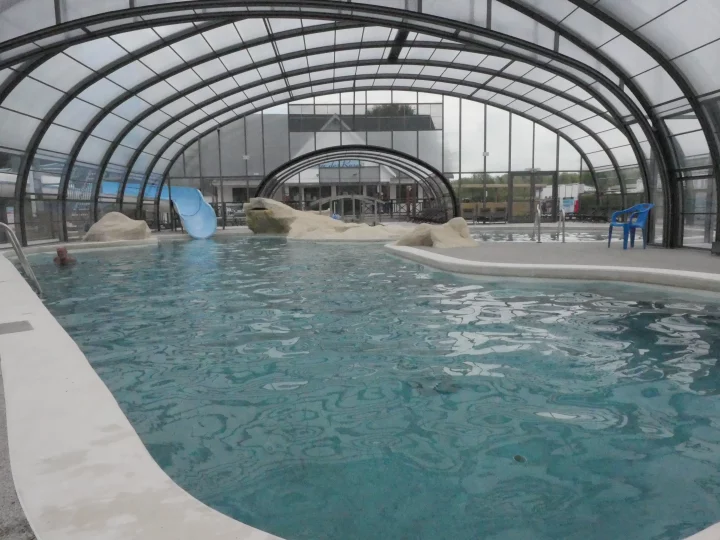 Piscine couverte avec toboggan et rochers.