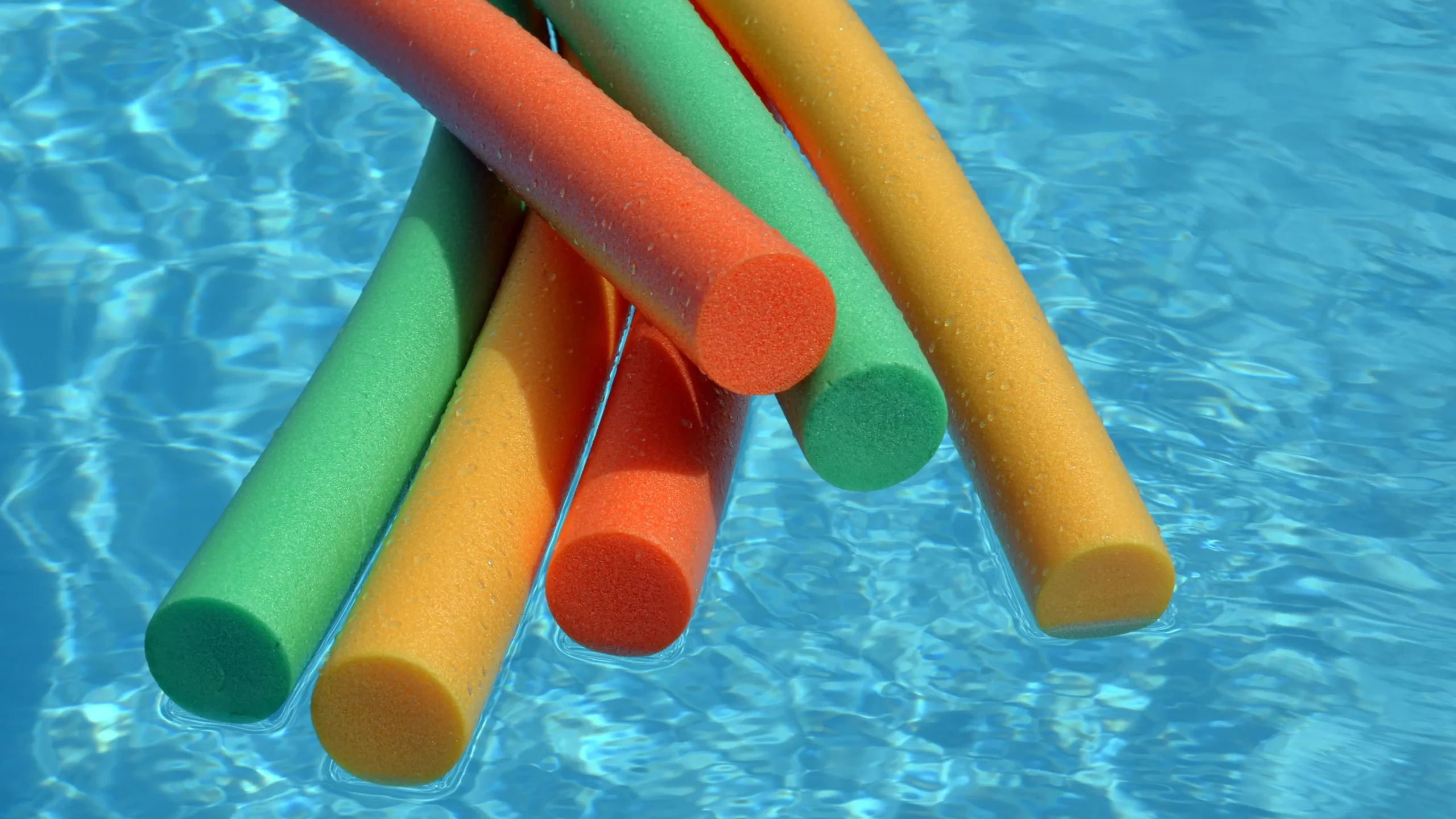 Tubes de piscine colorés flottants dans l'eau.