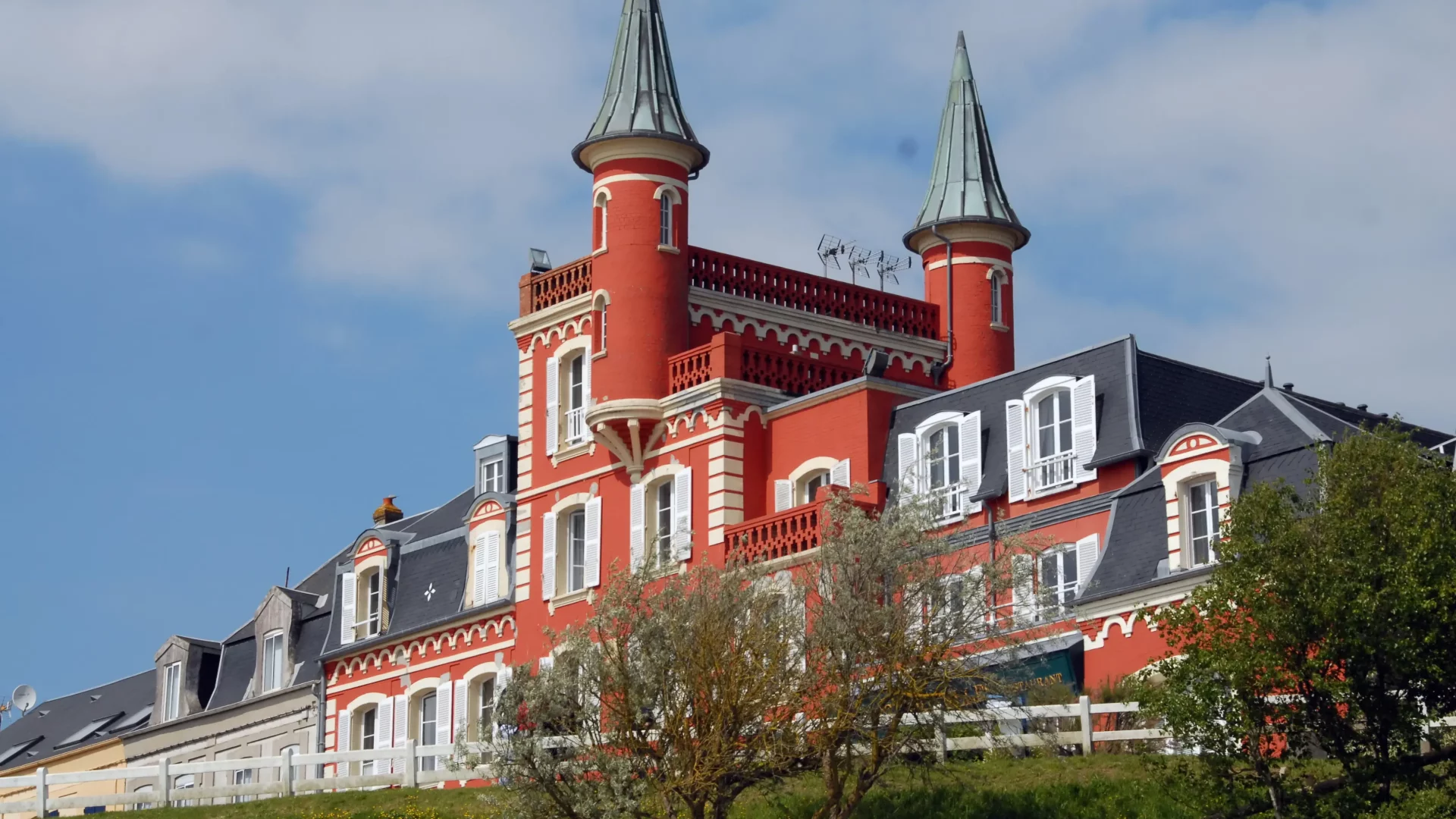 Bâtiment rouge avec des tourelles et des jardins.