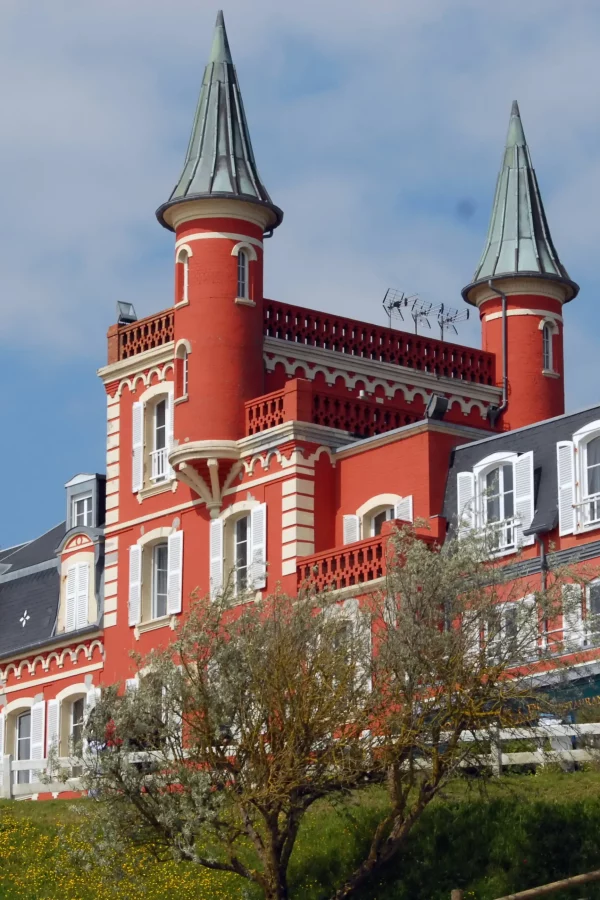Maison rouge avec tours et fenêtres blanches.