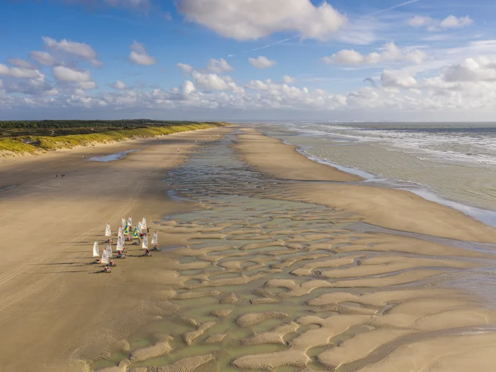 Chars à voile sur plage de sable, marée basse.