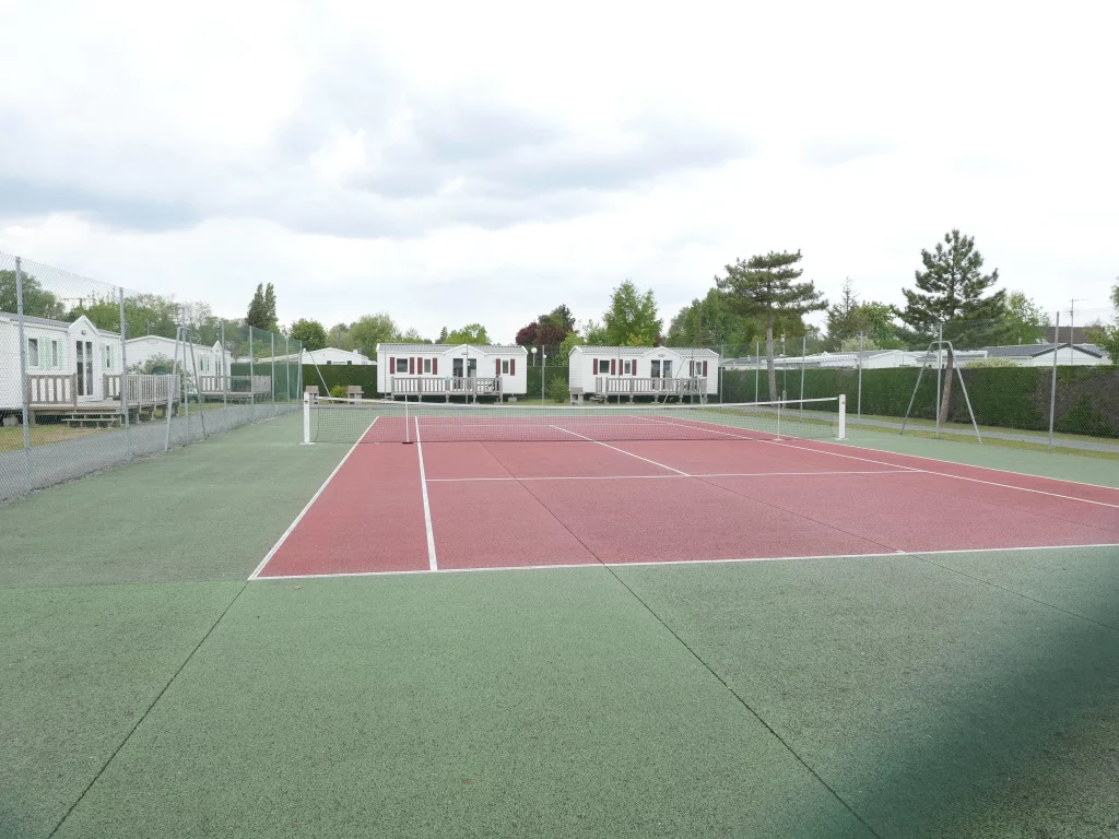 Court de tennis avec maisons en arrière-plan.