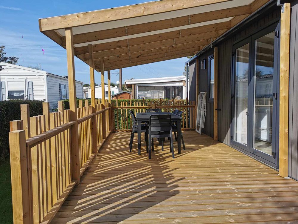 Terrasse en bois avec table et chaises noires.