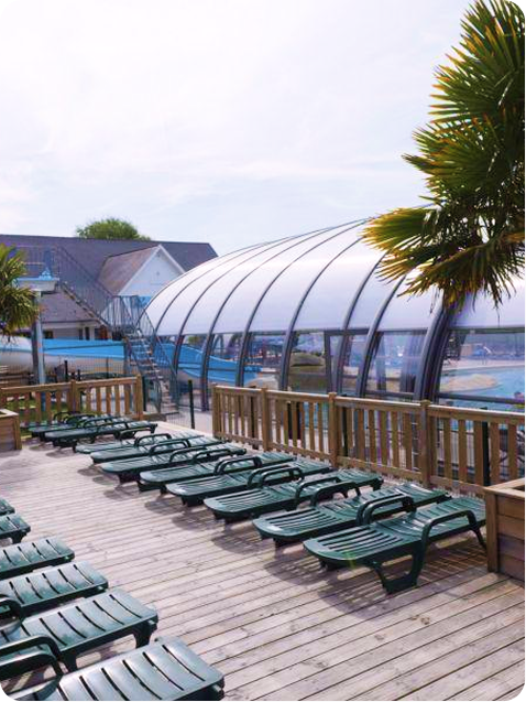 Terrasse avec chaises longues et piscine couverte.