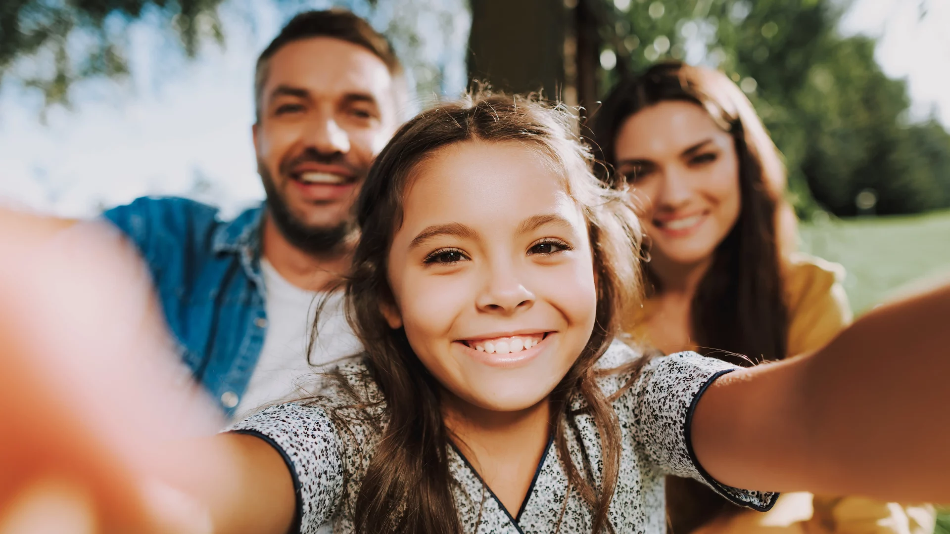 Famille souriante prenant un selfie en extérieur.