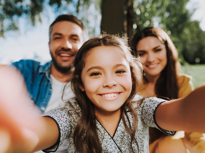 Famille souriante prenant un selfie en extérieur.