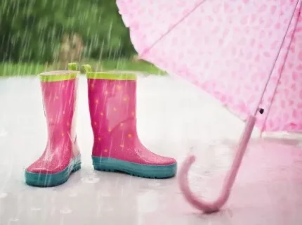 Bottes roses sous une pluie avec parapluie.